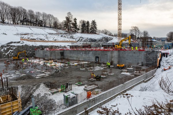 Byggeplass som viser grunnarbeid, betong, armeringsjern og heisekran.